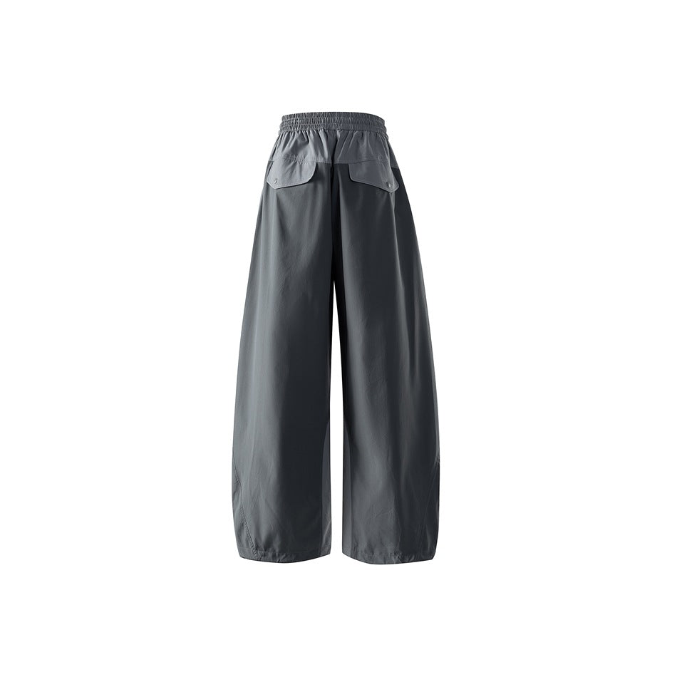 Back view of loose dark slate-gray trousers with an elastic waistband and two flap pockets.