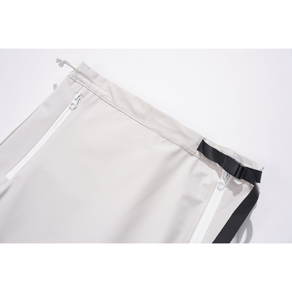 Close-up of an off-white skirt waistband with white zippers and a black adjustable buckle strap.