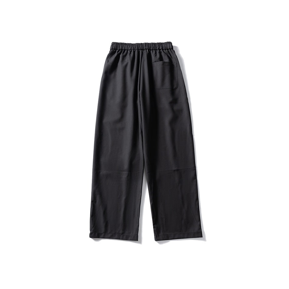 Back view of black wide-leg elastic-waist trousers with a single patch pocket