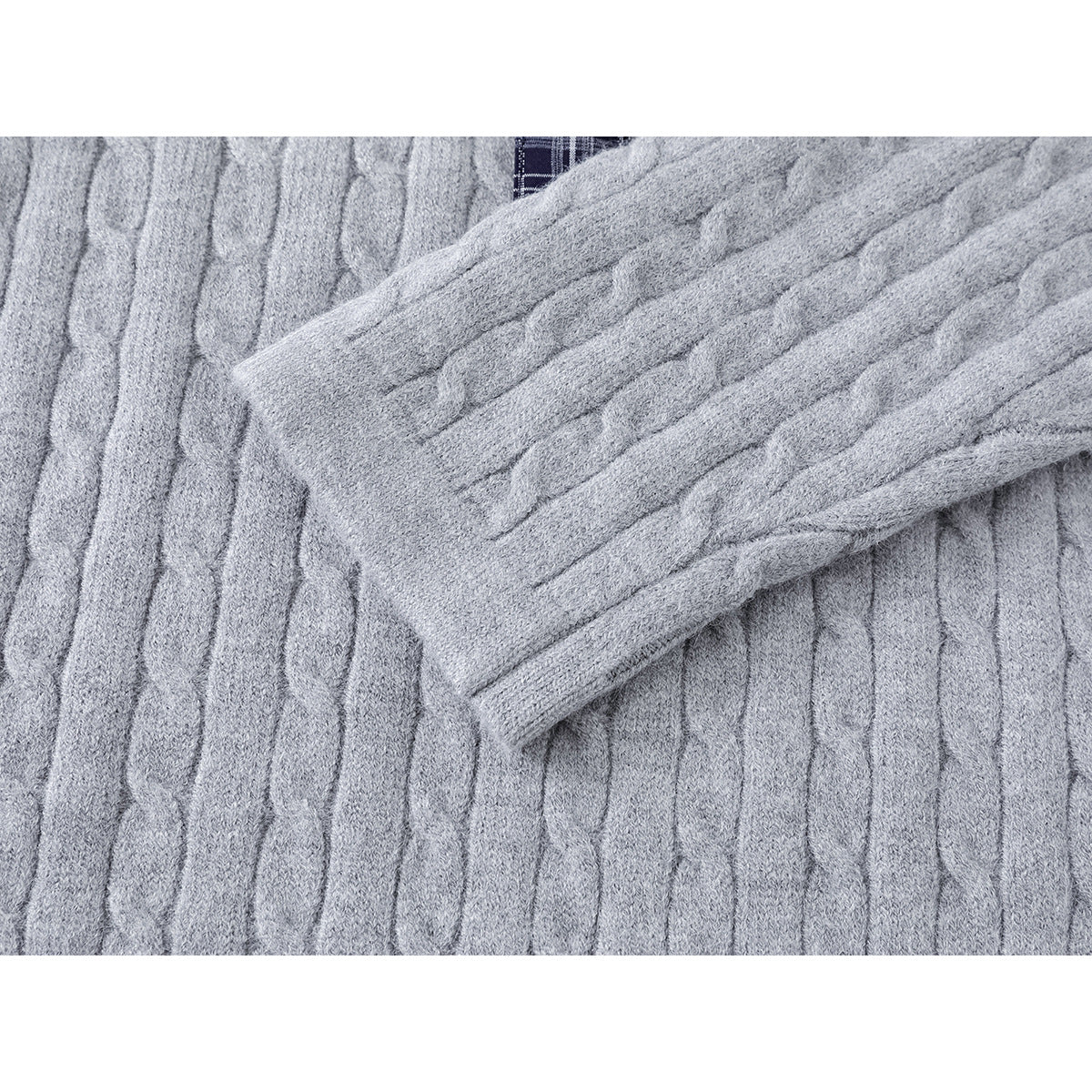 Close-up of a light gray cable-knit sleeve laid across the sweater body.