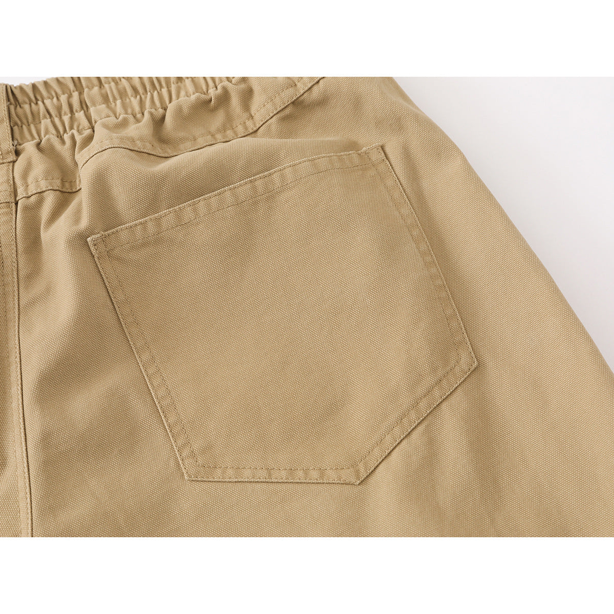 Close-up of tan trousers showing the elastic back waistband and a large rear pocket.