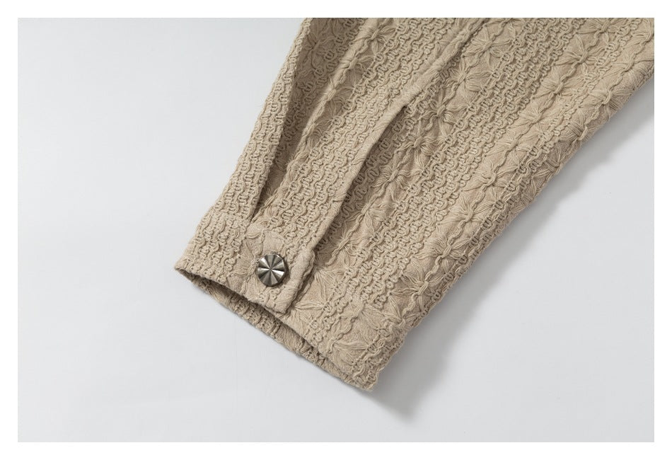 Beige sleeve cuff with raised floral stitching and a round silver snap button.