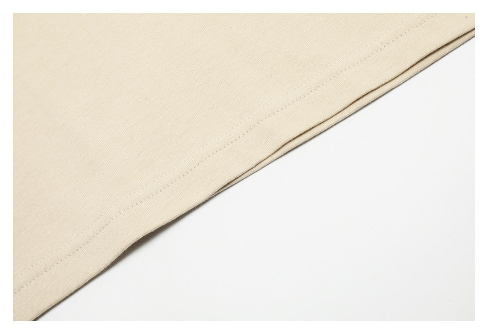 Close-up of a light beige garment hem with a neat line of stitching.