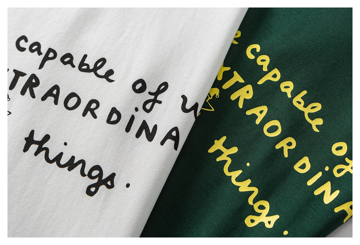 Close-up of white and dark green shirts with black and yellow English text prints.