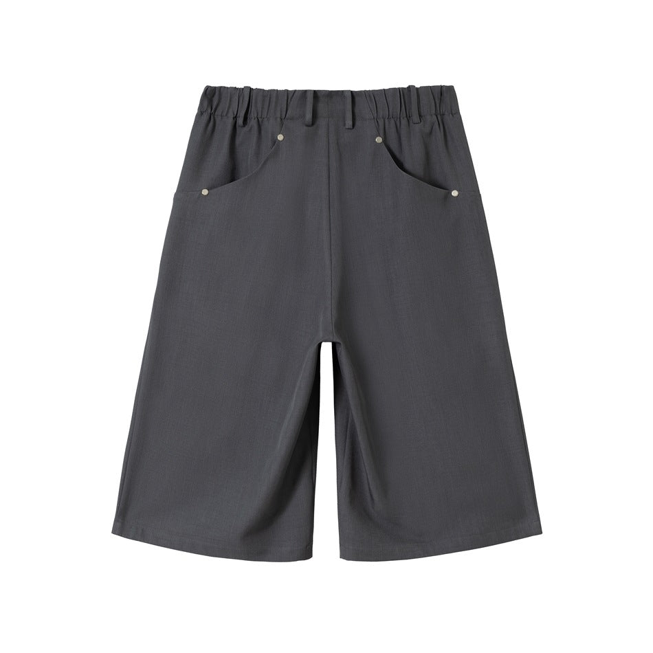 Front view of charcoal gray wide-leg shorts with an elasticized waistband, belt loops and curved rivet-trimmed pockets.