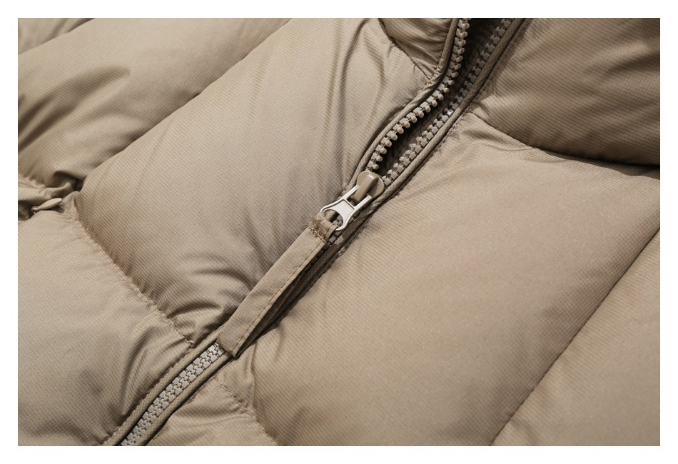 Close-up of the taupe puffer jacket’s front zipper and quilted panels.