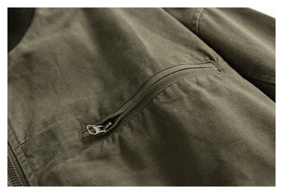 Close-up of an olive jacket with a curved zippered pocket and visible fabric texture.