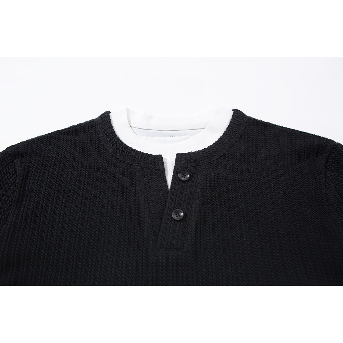 Close-up of a black ribbed long-sleeve henley neckline with two buttons, layered over a white crew-neck shirt.