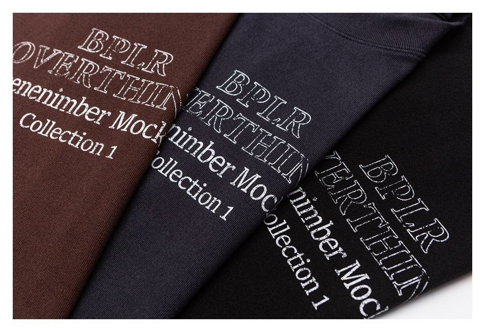 Close-up of brown, charcoal, and black garments with white printed text artwork.