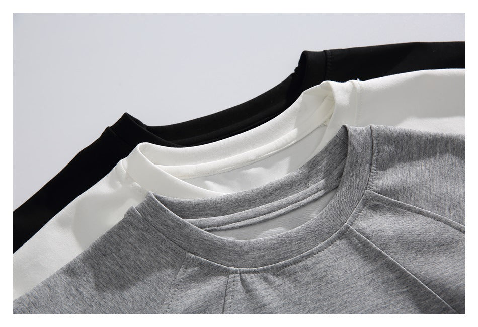 Gray, white, and black crew-neck tops overlap, showing their collars and shoulder seams.
