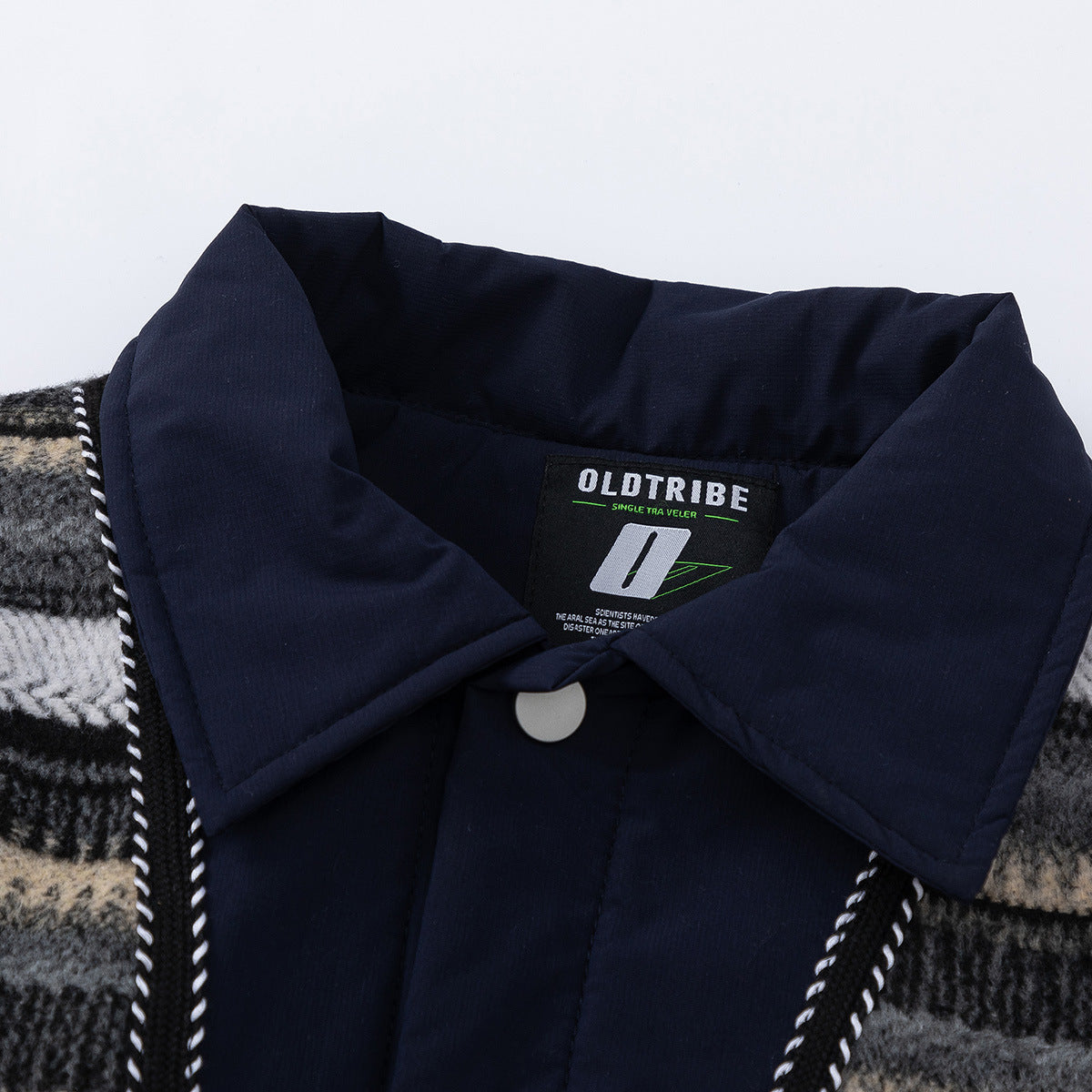 Close-up of a navy collar and sewn-in label on a black, gray, and cream plaid garment.