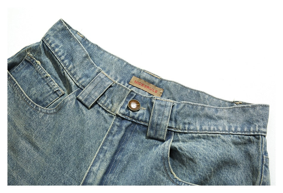 Close-up of light blue jeans showing the waistband, button, belt loops and front pocket.