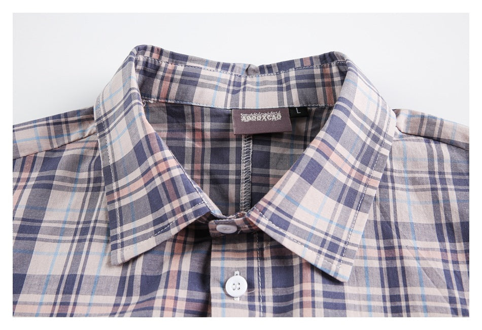 Close-up of a pale plaid shirt collar, white buttons, and sewn-in neck label.