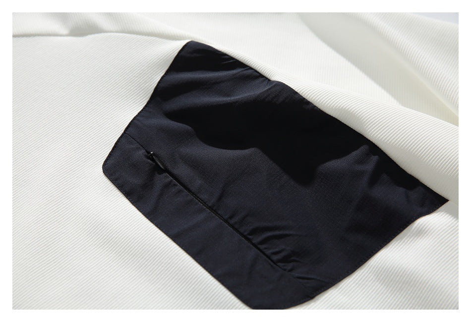 Close-up of a black patch pocket on the white ribbed shirt.