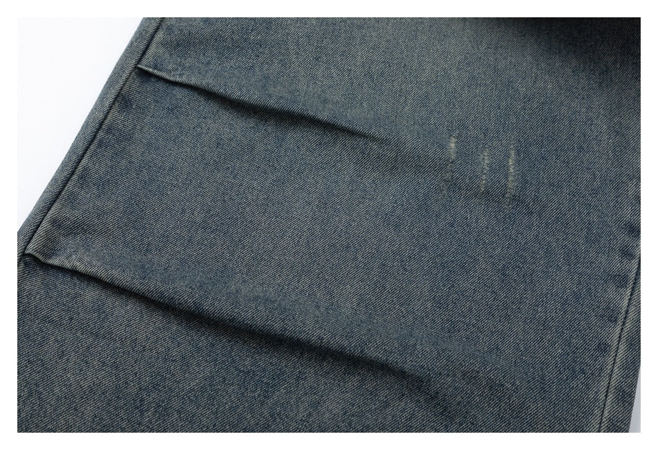 Close-up of a back pocket on faded blue-gray jeans, showing subtle distressed marks.