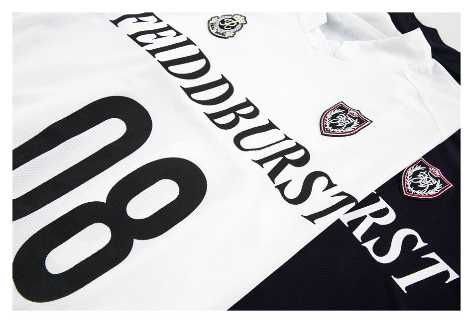 Close-up of a white and navy jersey with bold black lettering, a large number 08, and embroidered shield crests.