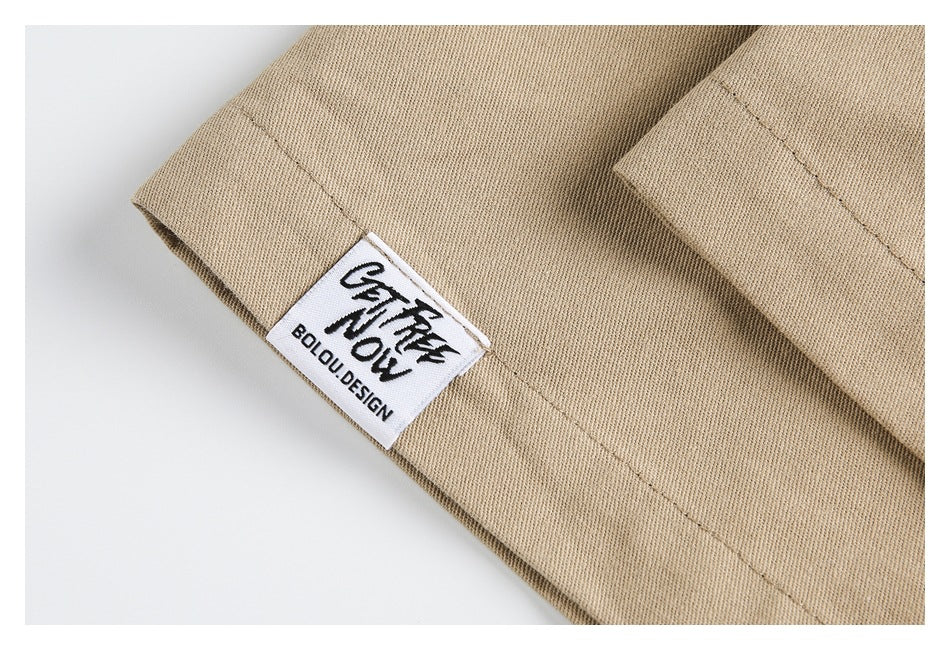 Close-up of a tan jacket sleeve with a sewn white label bearing black lettering.