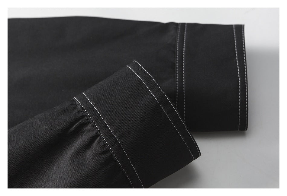 Close-up of black garment cuffs with parallel white stitching.