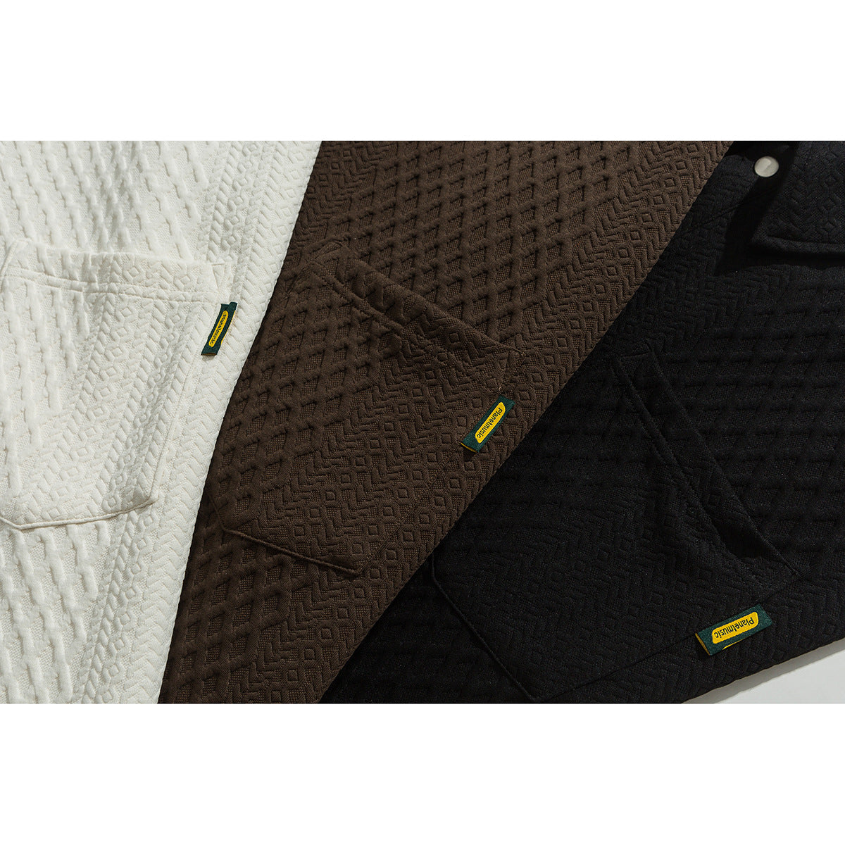 Close view of cream, dark brown, and black textured collared shirts with chest pockets and small woven labels.