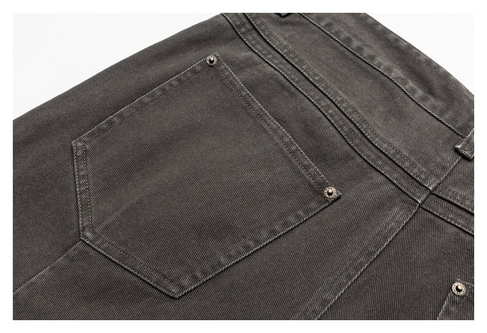 Close-up of a back pocket on dark charcoal pants, with visible topstitching and metal rivets.