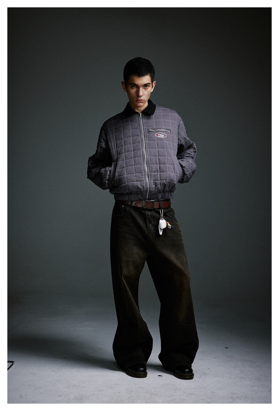 Model wearing a charcoal quilted jacket with a black collar, front zipper, and chest patch.
