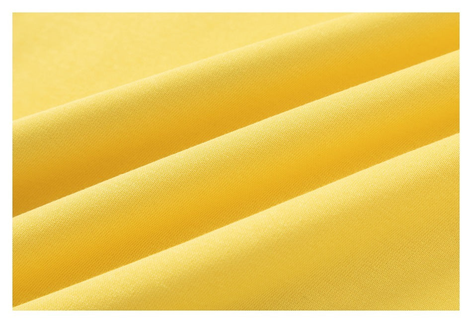Macro view of smooth yellow sweatshirt fabric folded into diagonal ridges.