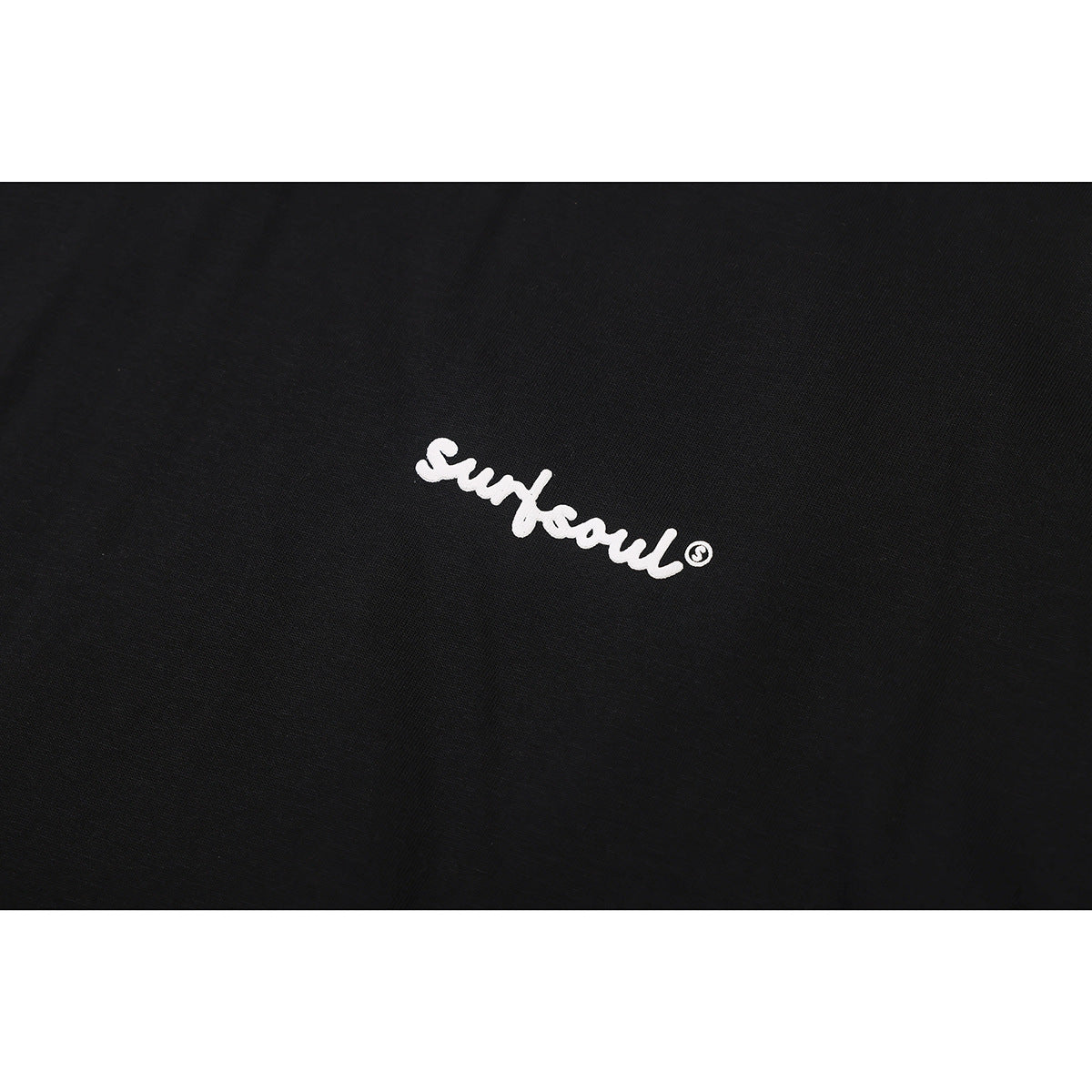 Close-up of a small white cursive “Surf soul” print on black fabric.