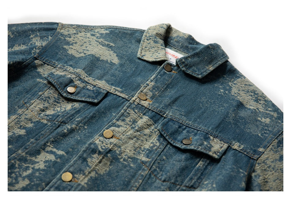 Cropped front view of a blue distressed denim jacket laid flat, with a pointed collar and buttoned chest pockets.