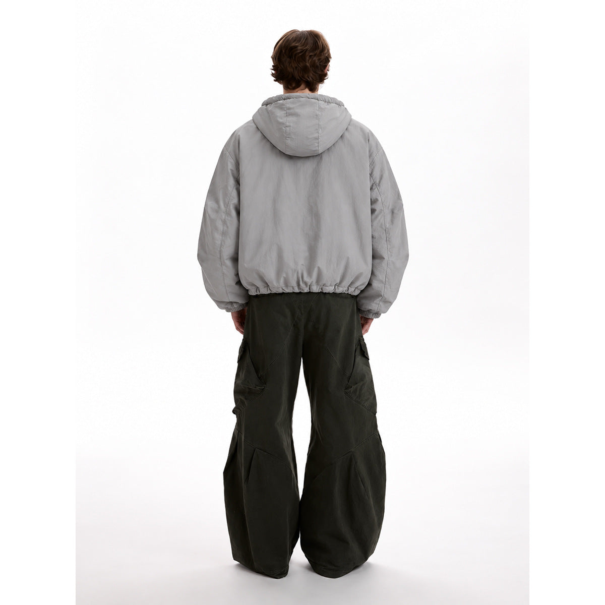 Rear view of a model wearing a light gray hooded jacket with elastic cuffs and a gathered hem.