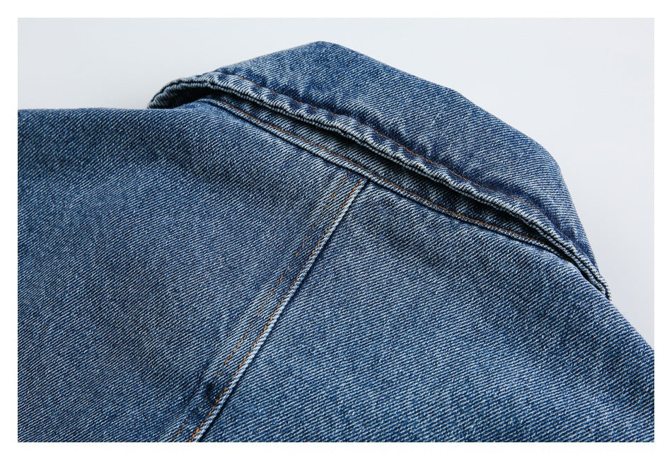 Close-up of the folded collar and shoulder seam of a blue denim jacket.