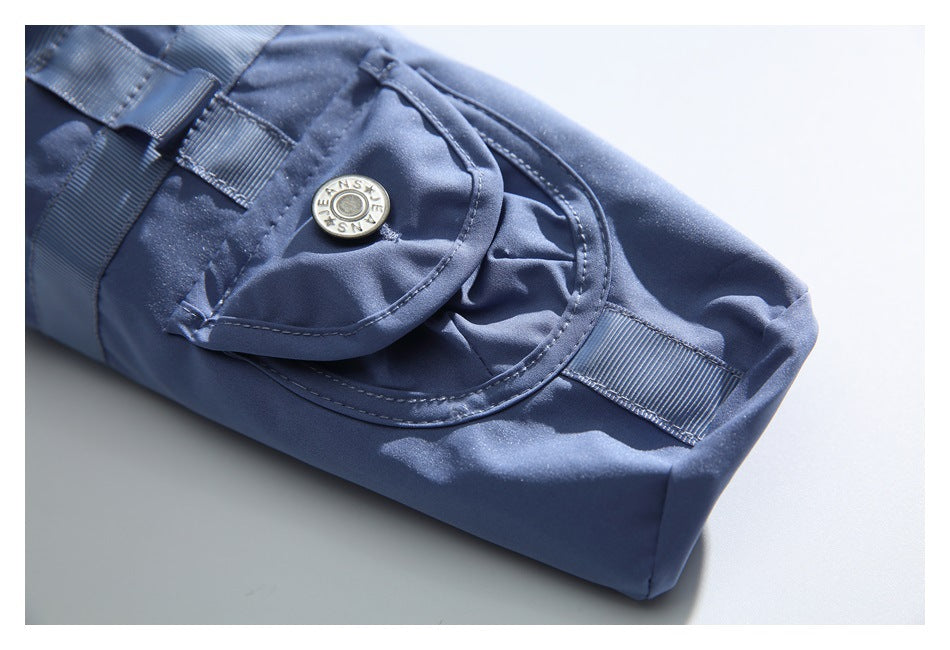 Close-up of blue cargo trousers showing a snap-button flap pocket and stitched webbing tabs.