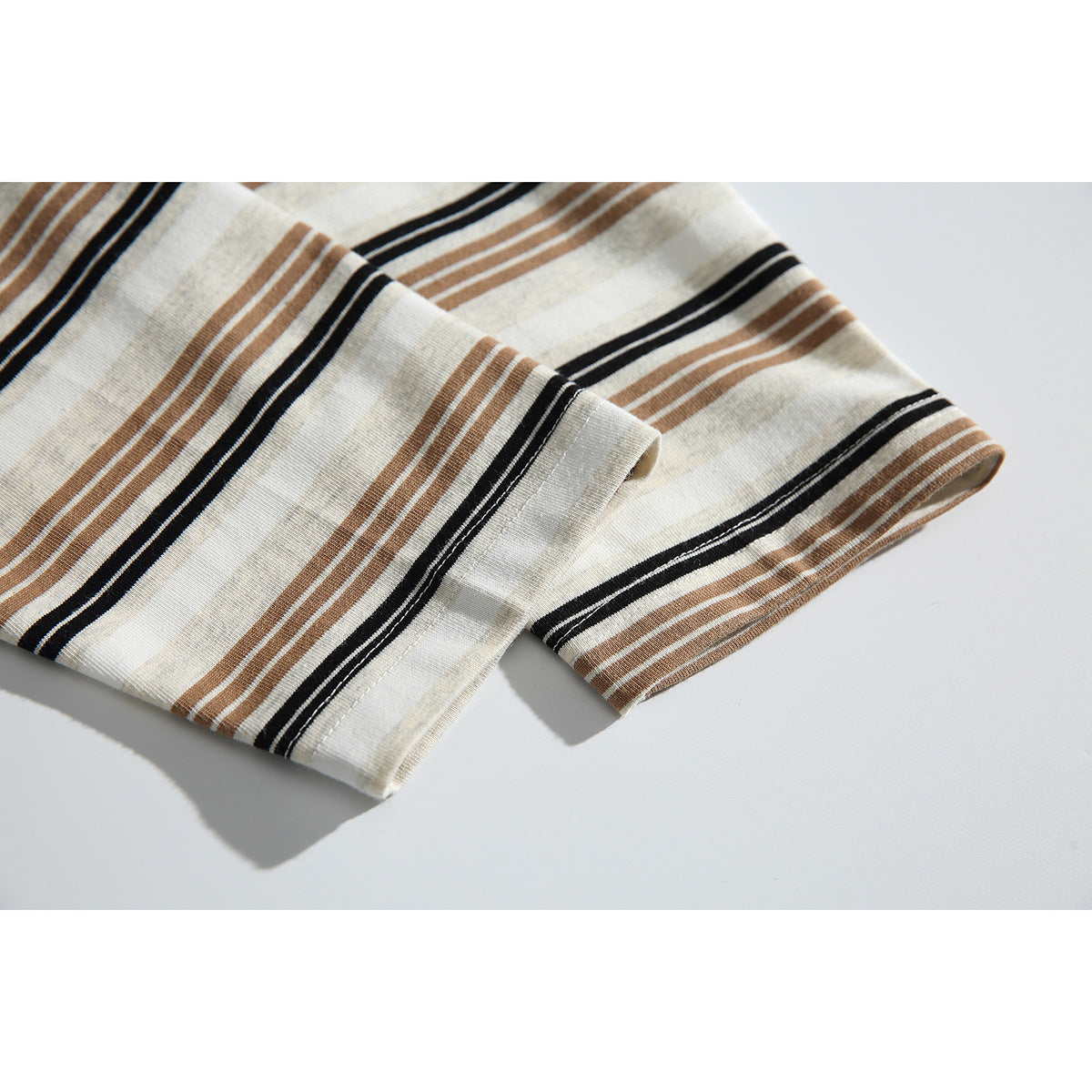 Close-up of the striped shirt's sleeve and folded cuff in ivory, tan, and black.
