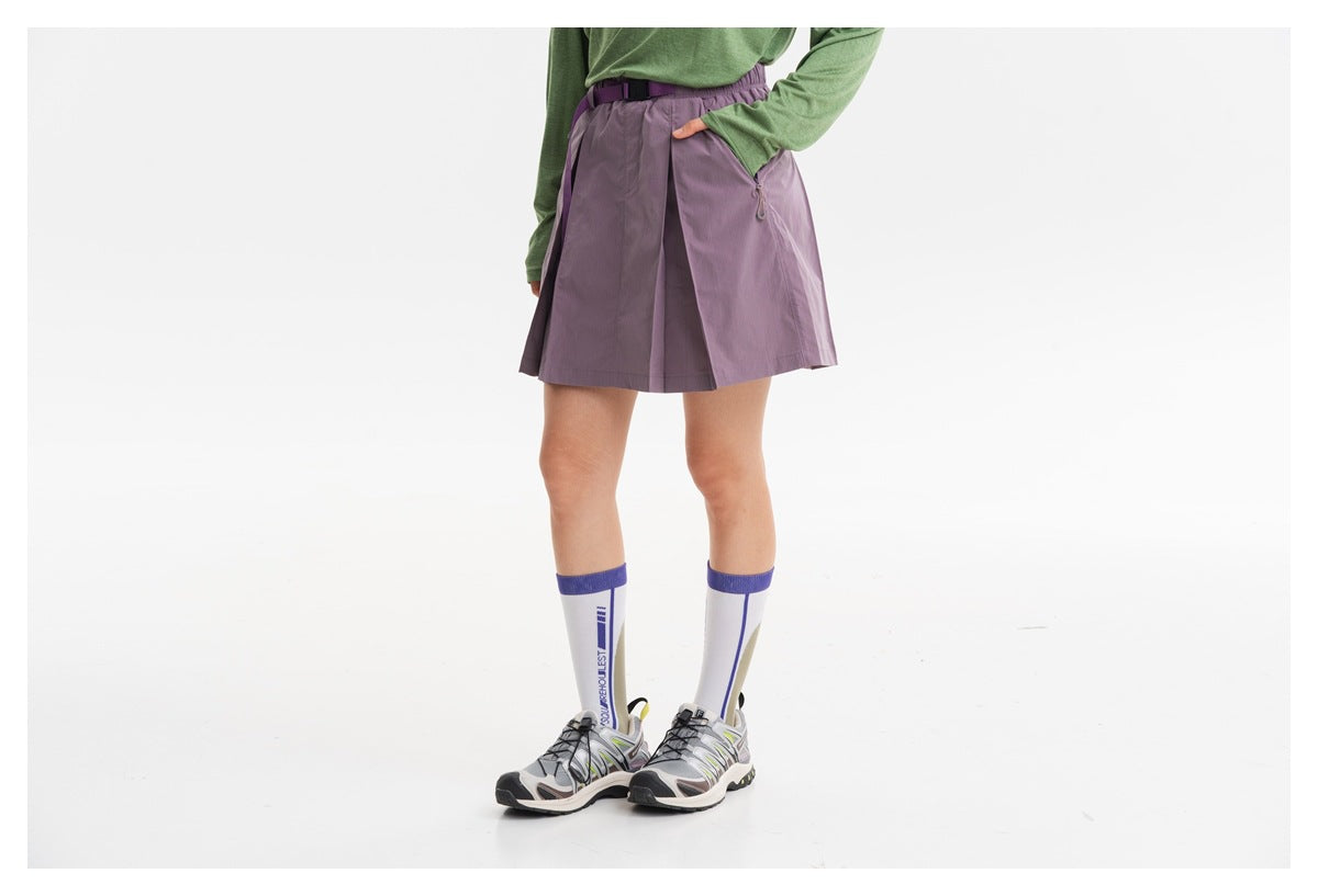 Cropped model wearing a lavender pleated skirt with an elastic waist, belt and zip pocket.