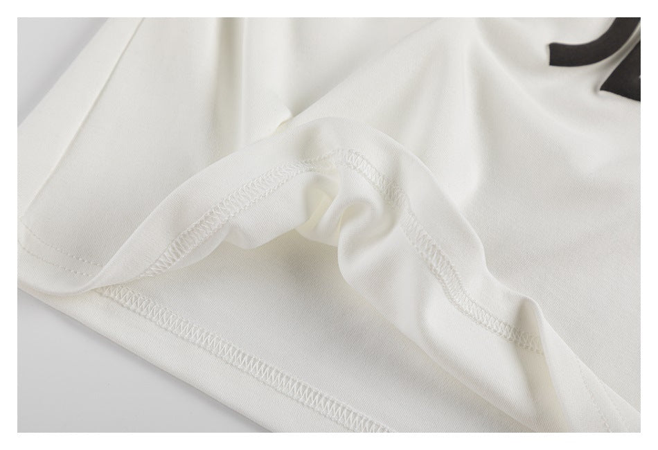 Close-up of white garment fabric and overlocked seams, with a small portion of black print at the edge.