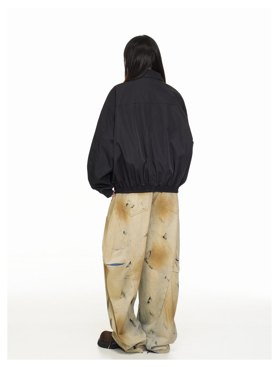 Rear view of a model wearing a black jacket with a back yoke seam and elasticated hem.