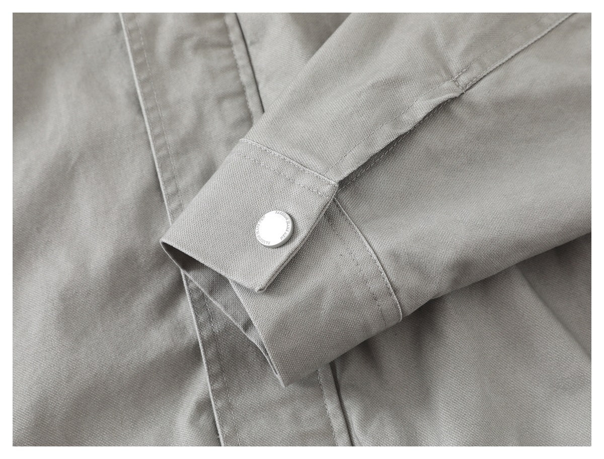 Close-up of a light gray jacket sleeve cuff with a round silver button.