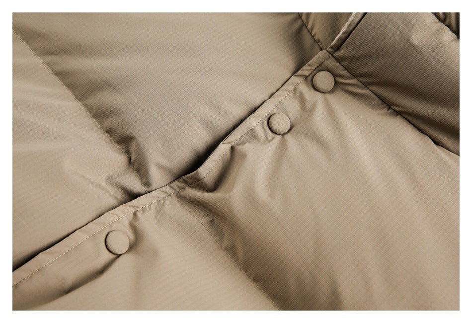 Close-up of beige padded fabric with a diagonal snap-fastened seam and covered buttons.