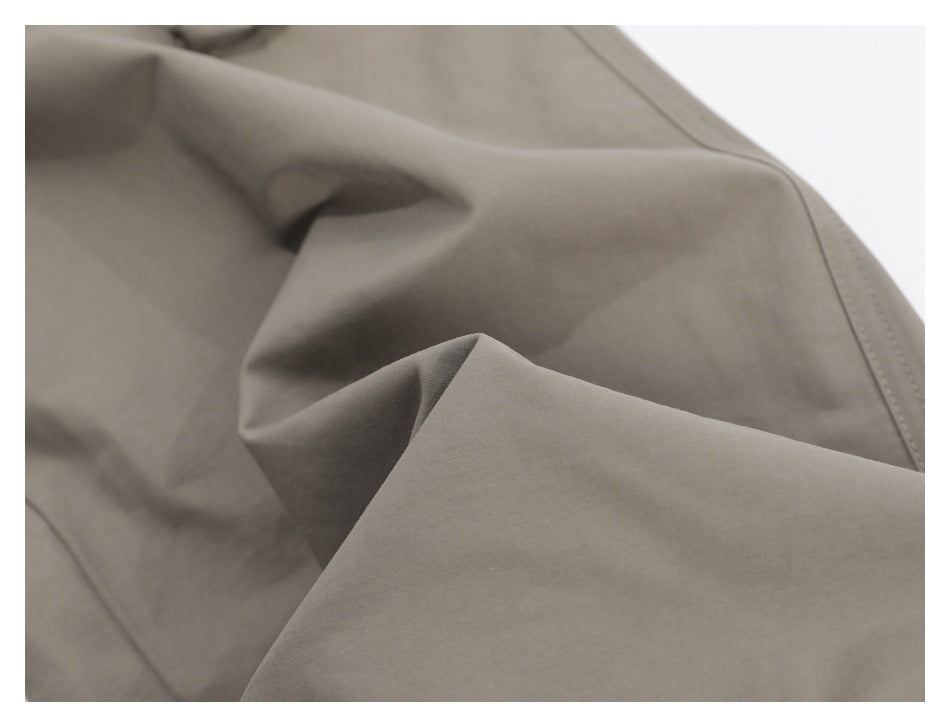 Close-up of taupe fabric folds and stitched seam on the garment.