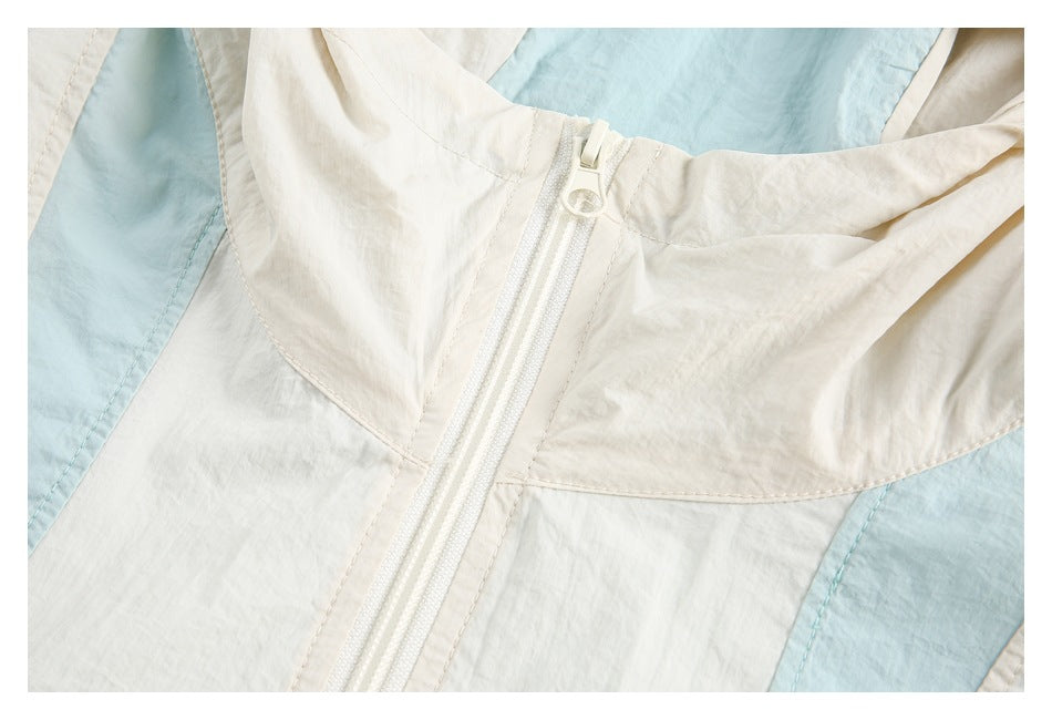 Close-up of the cream jacket’s front zipper, hood seam, and pale blue contrast panels.