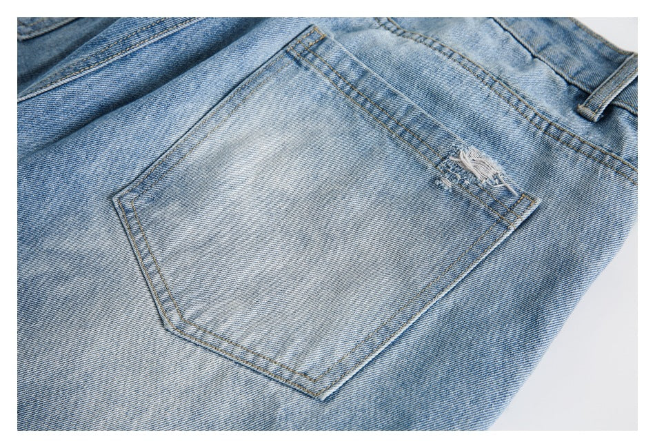 Close-up of a light blue jeans back pocket with a small distressed tear near the top edge.