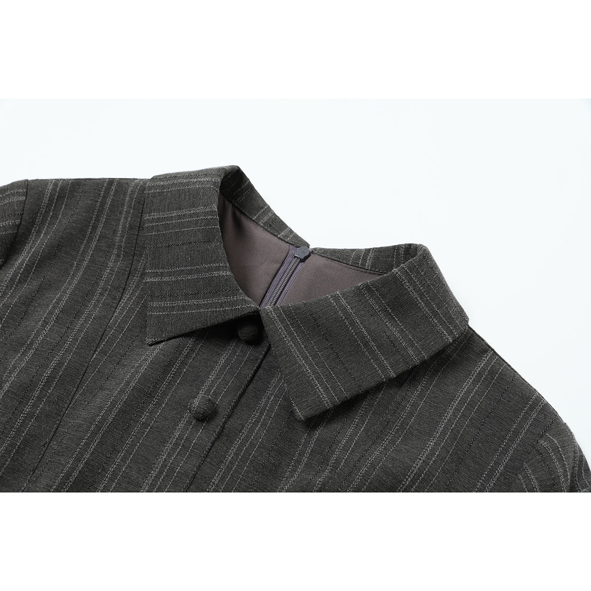 Close-up of a charcoal pinstriped garment's pointed collar, front buttons, and back zipper.