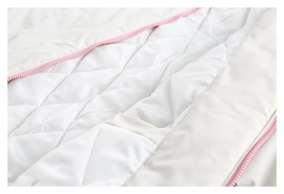 Close-up of a white garment's quilted lining and pink zipper trim.
