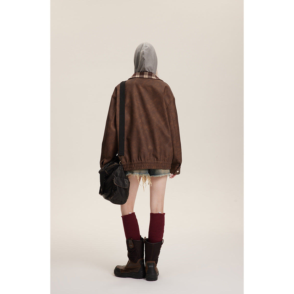 Back view of a model wearing the brown jacket, showing its plaid collar and gathered hem.