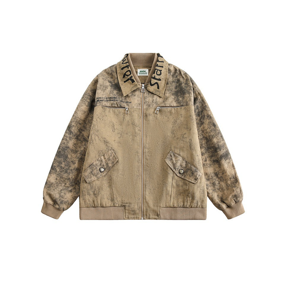 Front view of a brown mud-dyed zip jacket with lettered collar, chest zip pockets, flap pockets and ribbed hem