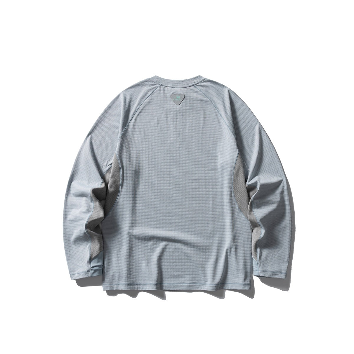 Back view of a light blue-gray long-sleeve raglan shirt with a small upper-back patch and reflective sleeve dots.