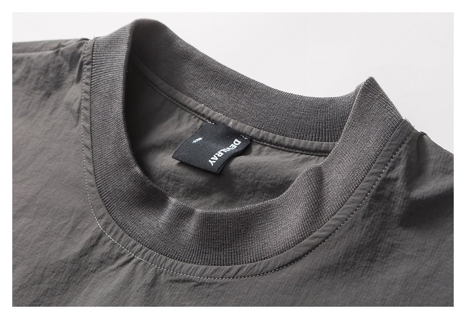 Close-up of a charcoal gray top showing its ribbed crew neck and black inner brand label.