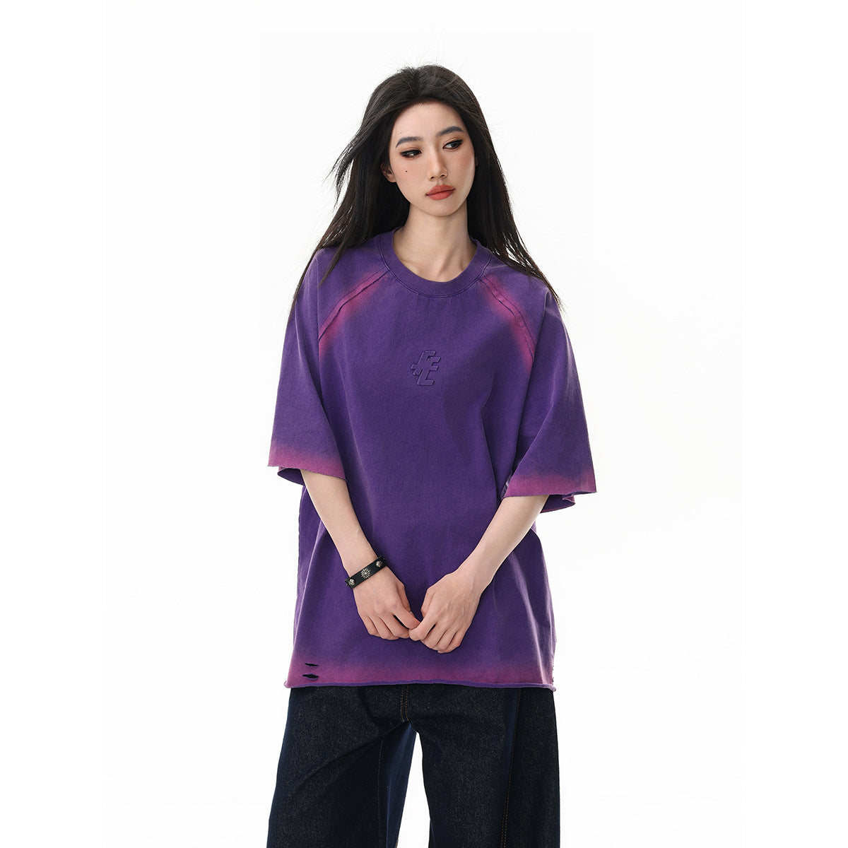 Model wearing an oversized purple T-shirt with pink fading at the shoulders and sleeves, paired with dark jeans.
