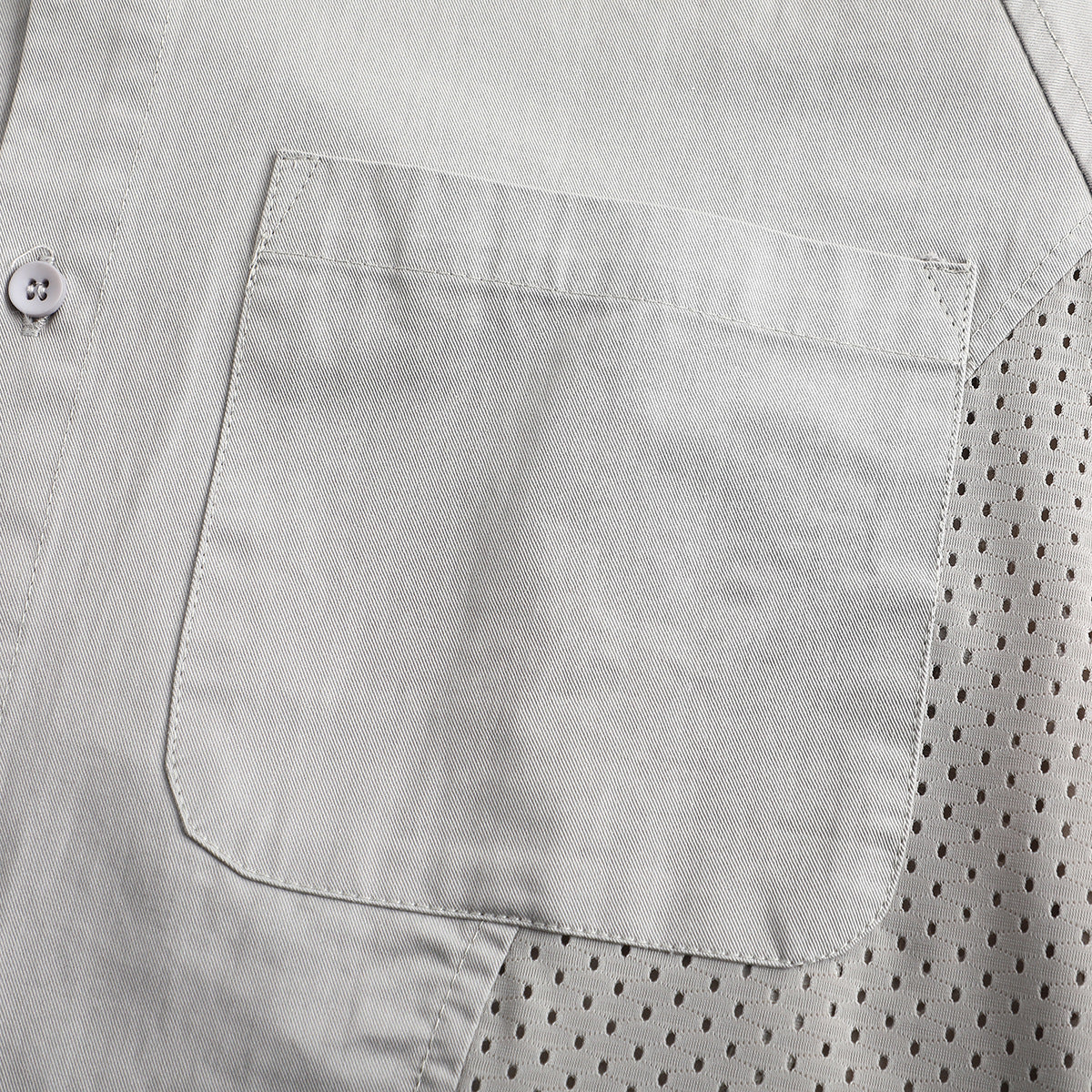 Close-up of a light gray shirt's large patch pocket beside a perforated mesh side panel.