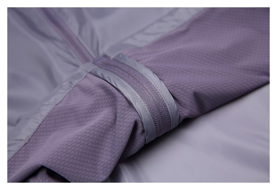 Close-up of gray-purple jacket fabric, a textured mesh panel, and a narrow zippered seam.