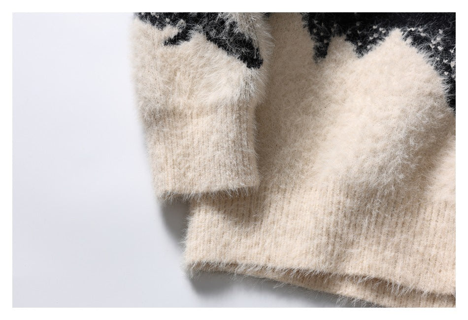 Close-up of an ivory fuzzy knit sweater's ribbed cuff and hem beneath a black-and-ivory pattern.